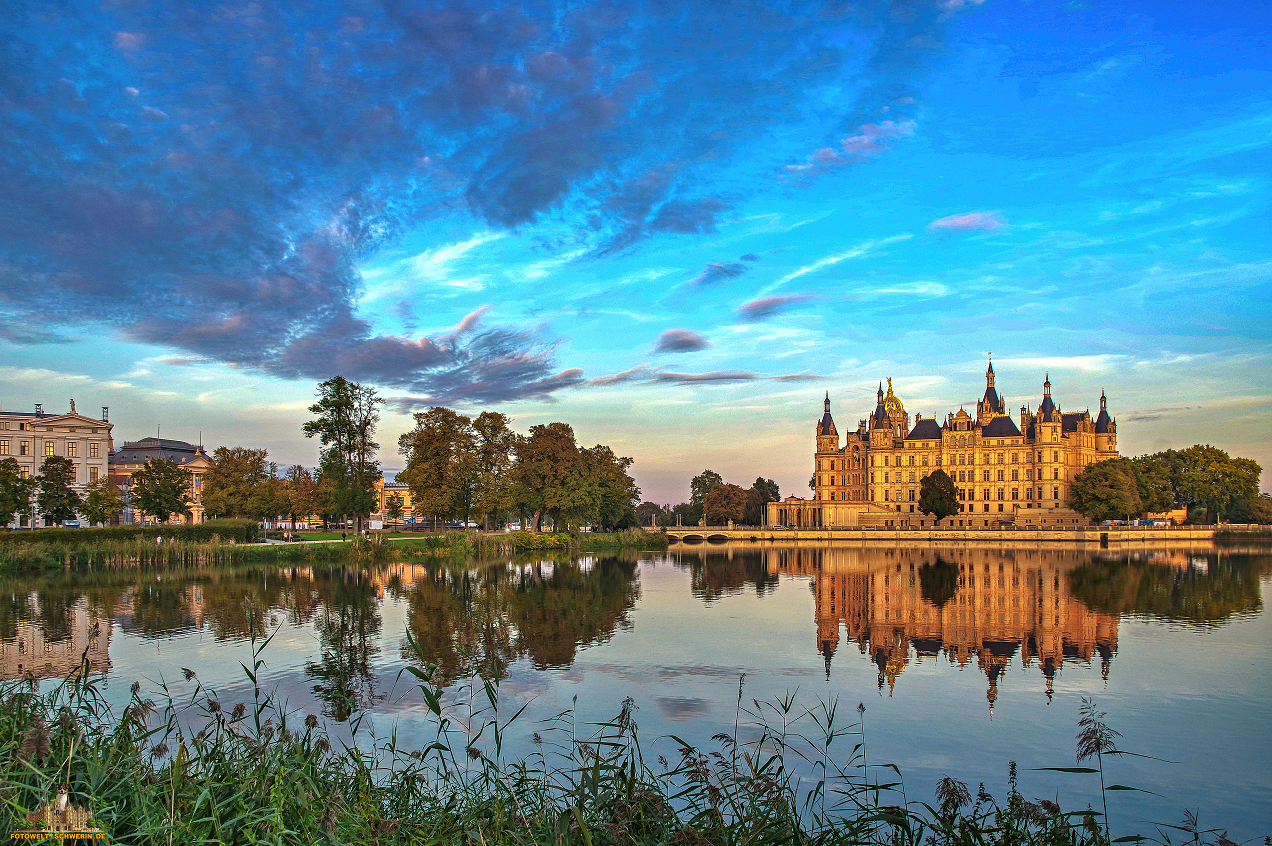 Schweriner Schloss im Abendlicht – Unser schönes Schloss ist ein echter Hingucker. Gerade am Abend, wenn die Sonne die Wolken in bunte Farben taucht, sieht das Schloss noch mal so schön aus. Kein Wunder, dass dieses Gemäuer kürzlich zum Weltkulturerbe erklärt wurde. Das Schloss ist auch im Kalender 2027 zu sehen. Hier könnt ihr ihn erhalten: https://fotowelt-schwerin.de
